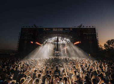 Crowd enjoying a night performance at Decibel Open Air 2024 festival with vibrant lights and a large outdoor stage.