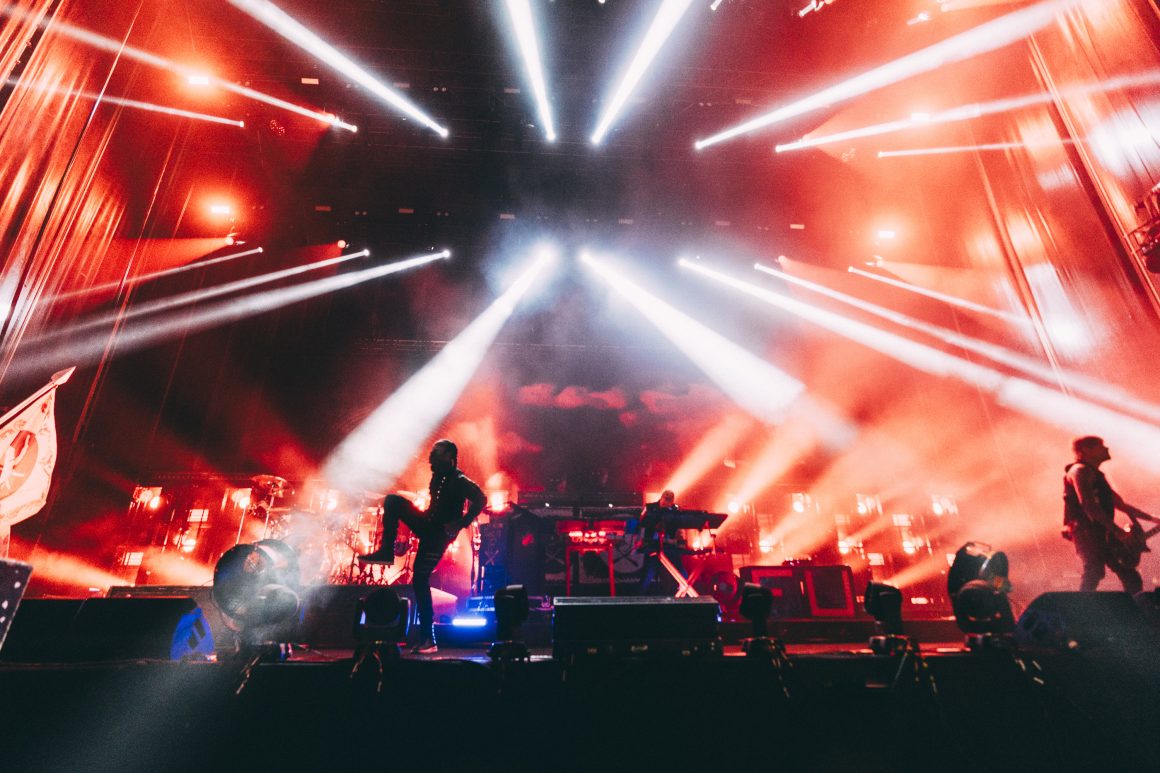 The Prodigy performing at Kalorama Madrid with intense red and white lighting effects, as the band members are silhouetted against a backdrop of smoke and lasers