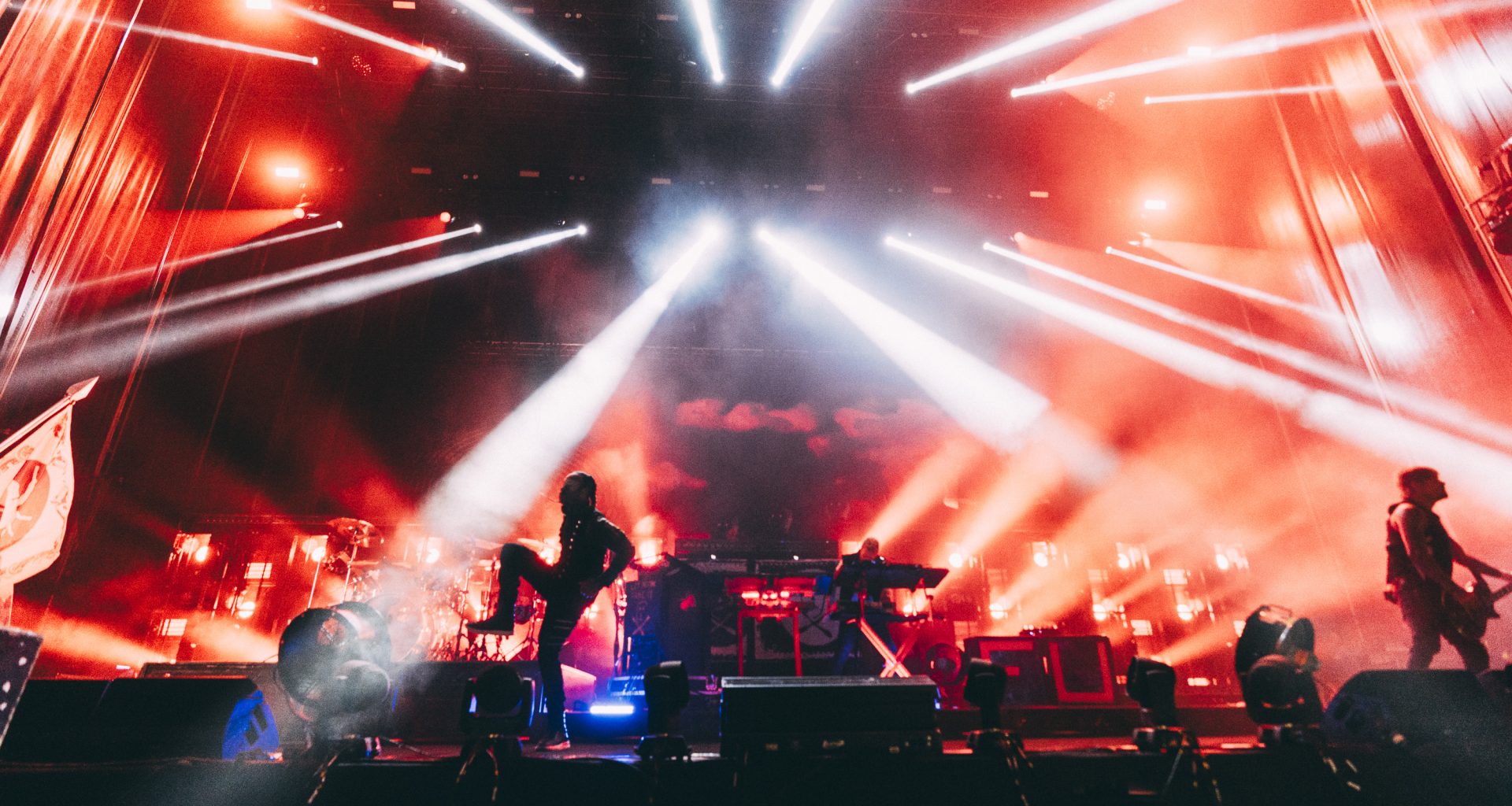 The Prodigy performing at Kalorama Madrid with intense red and white lighting effects, as the band members are silhouetted against a backdrop of smoke and lasers