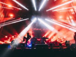 The Prodigy performing at Kalorama Madrid with intense red and white lighting effects, as the band members are silhouetted against a backdrop of smoke and lasers