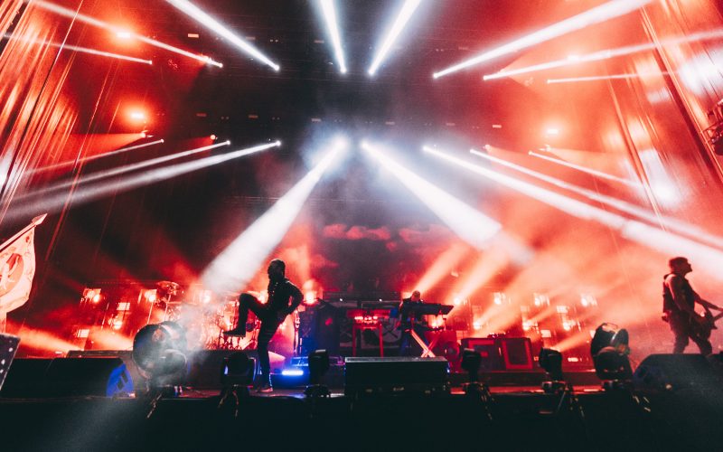 The Prodigy performing at Kalorama Madrid with intense red and white lighting effects, as the band members are silhouetted against a backdrop of smoke and lasers