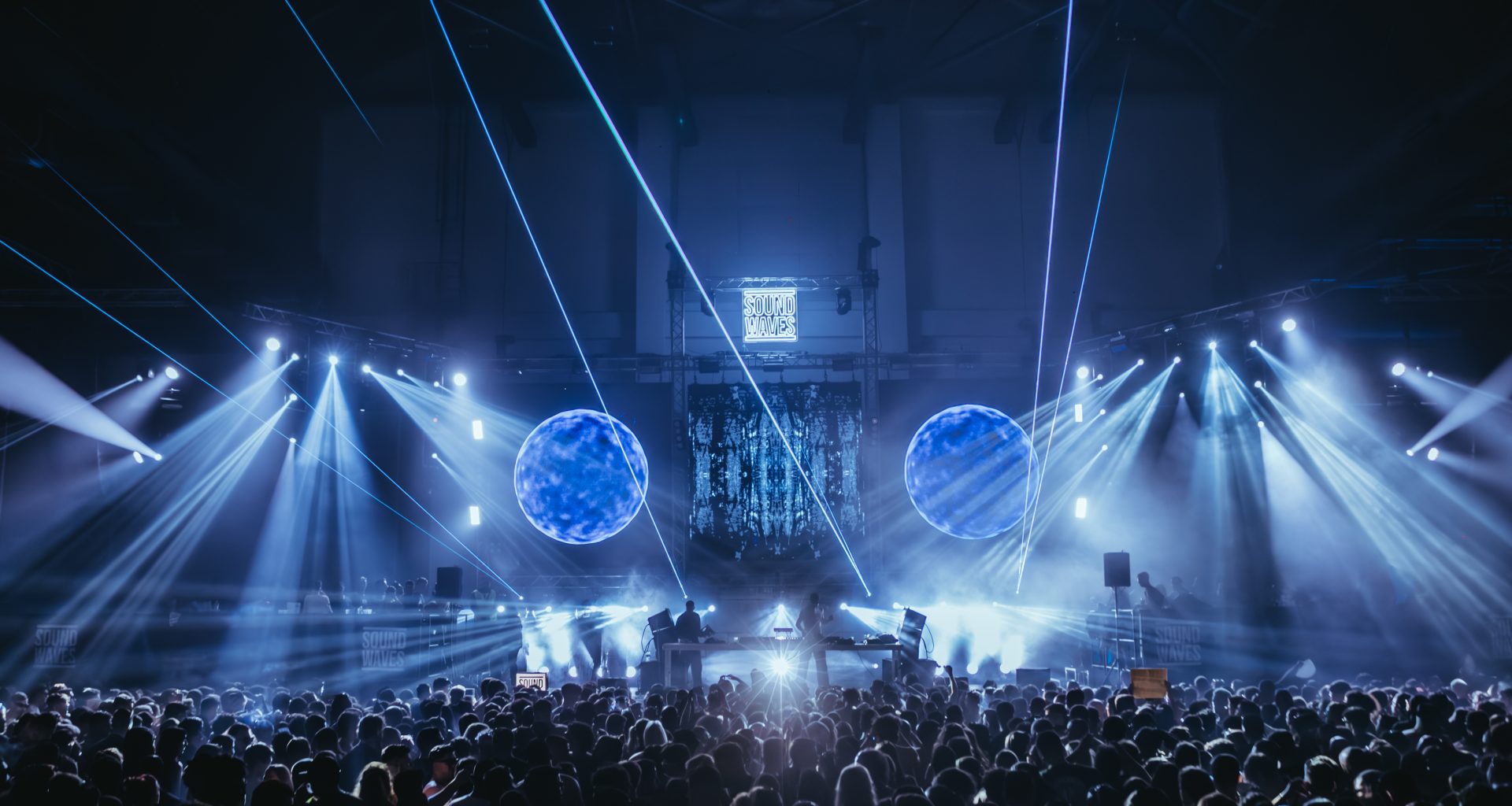 Atmospheric shot of the Sound Waves Winter Edition stage at Carlos Lopes Pavilion, featuring stunning laser visuals and a packed crowd under dynamic lighting.