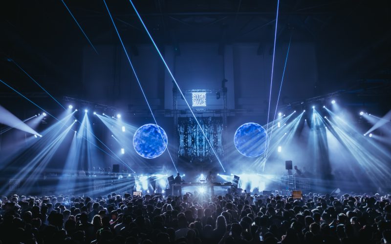 Atmospheric shot of the Sound Waves Winter Edition stage at Carlos Lopes Pavilion, featuring stunning laser visuals and a packed crowd under dynamic lighting.